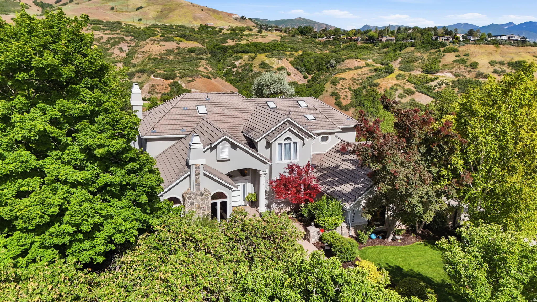 Hillside residence featuring a multi-level roofline, skylights, and multiple chimneys