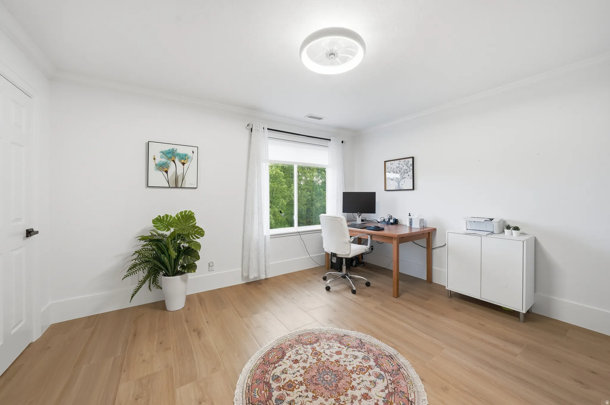 Bright room featuring light wood-finish flooring, crisp white walls, and a recessed window with natural light