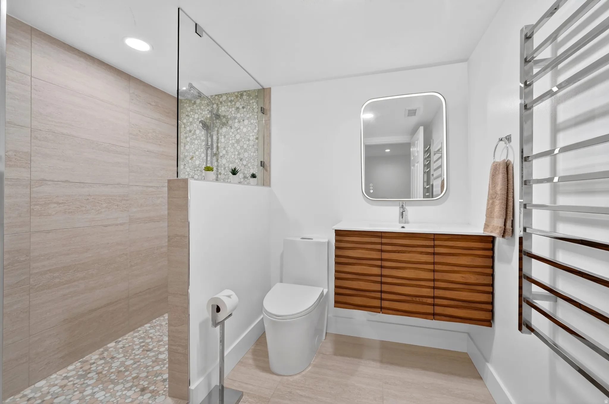 Contemporary bathroom featuring a floating wood-grain vanity with integrated sink, a rectangular illuminated mirror, and a sleek wall-mounted toilet