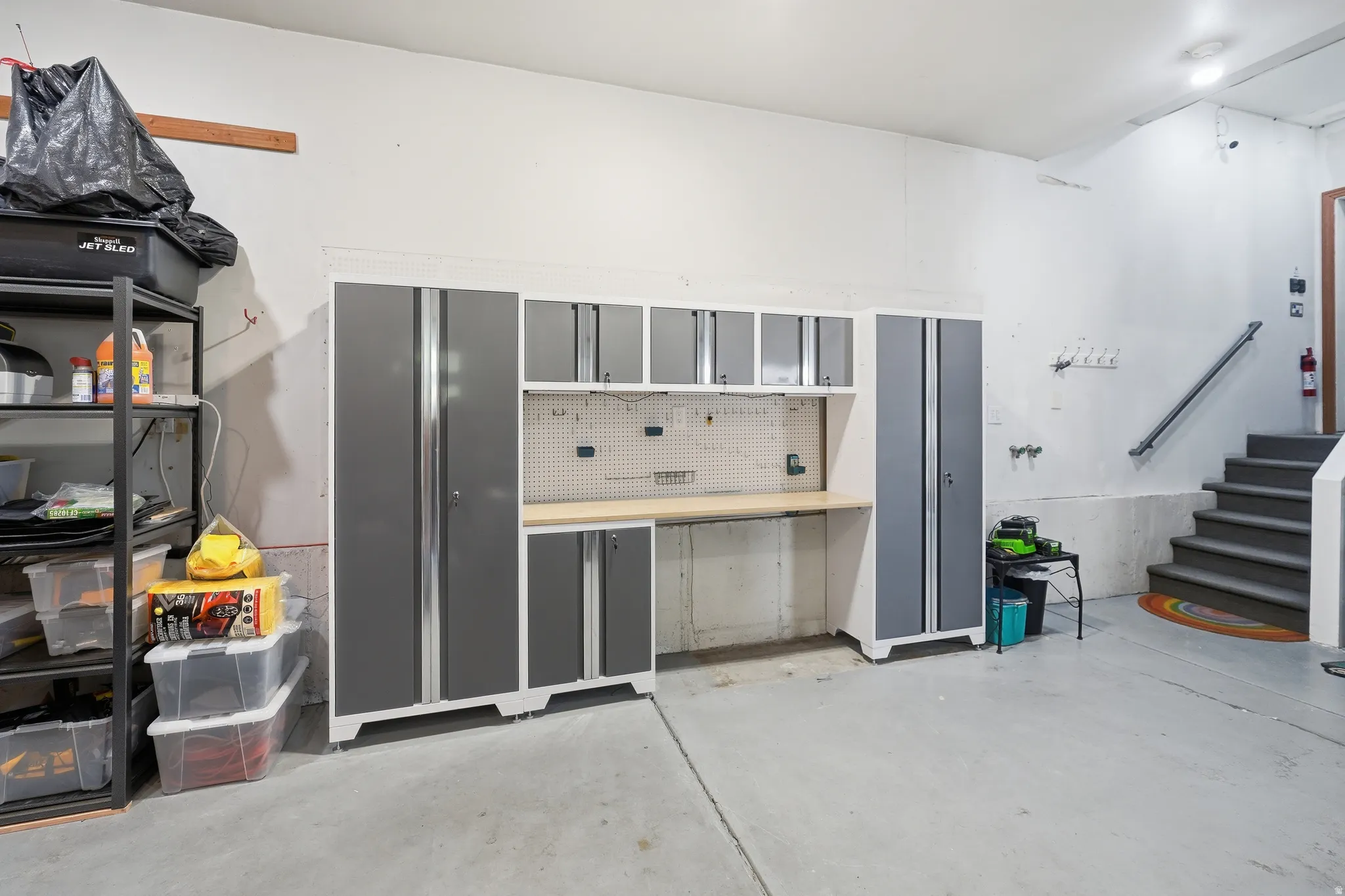 Garage featuring extensive built-in cabinetry, an integrated workbench, and pegboard storage