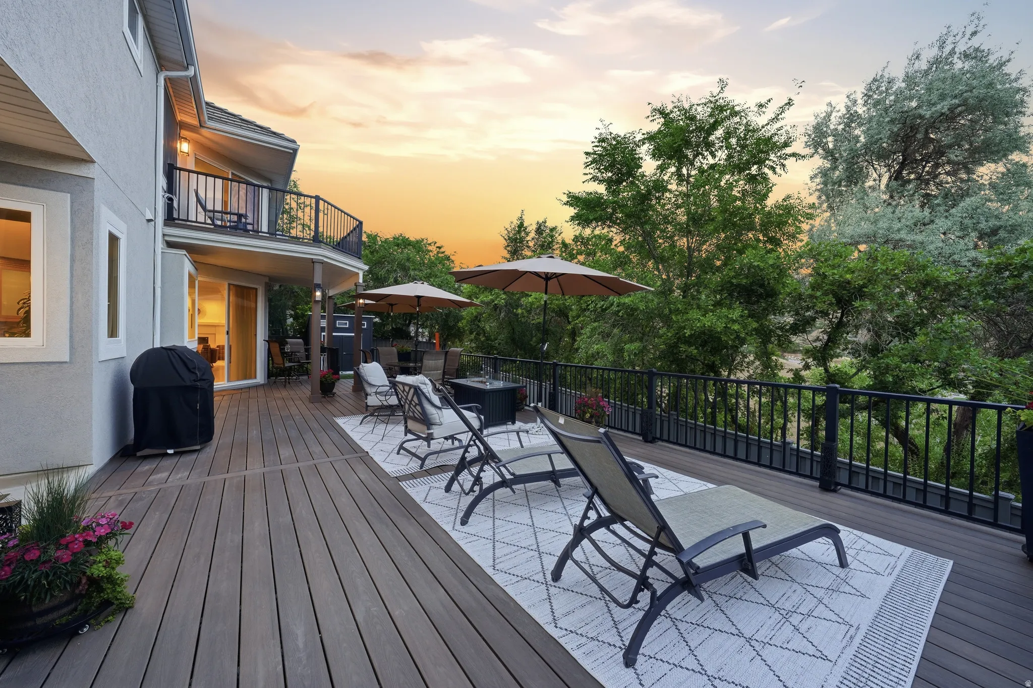Spacious multi-level deck featuring composite decking, black iron railings, and mature perimeter trees
