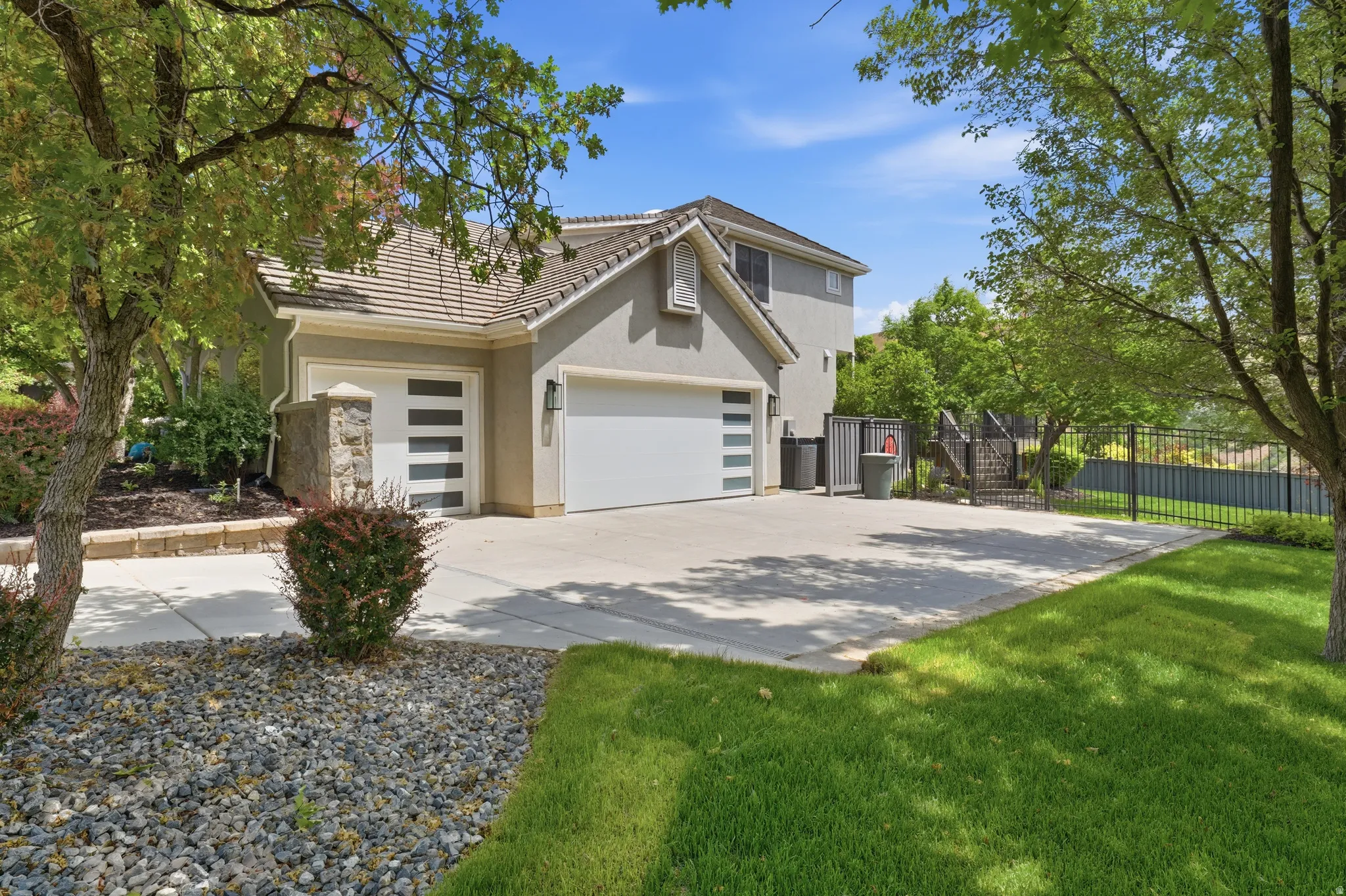 Stucco exterior with a tile roof and two garage doors, one featuring modern frosted glass inserts