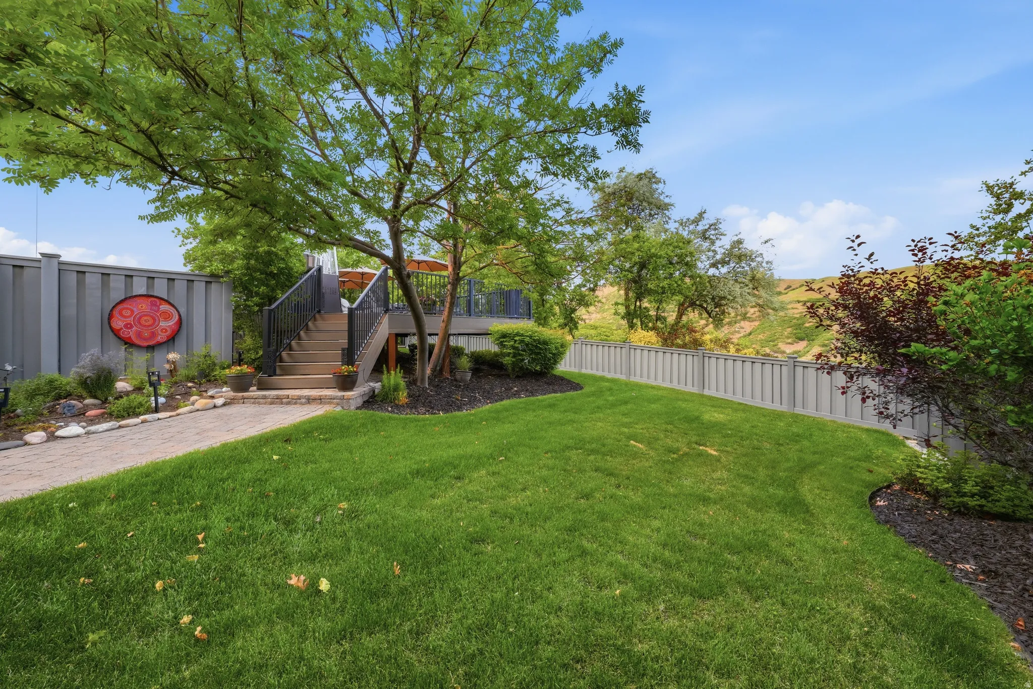 Landscaped backyard featuring a staircase leading to an upper deck