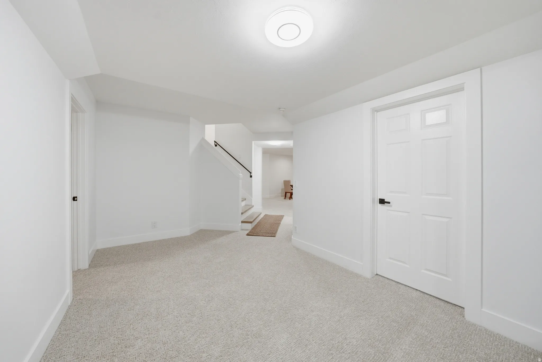Expansive open space featuring light-colored carpeting, white walls, and a recessed ceiling light