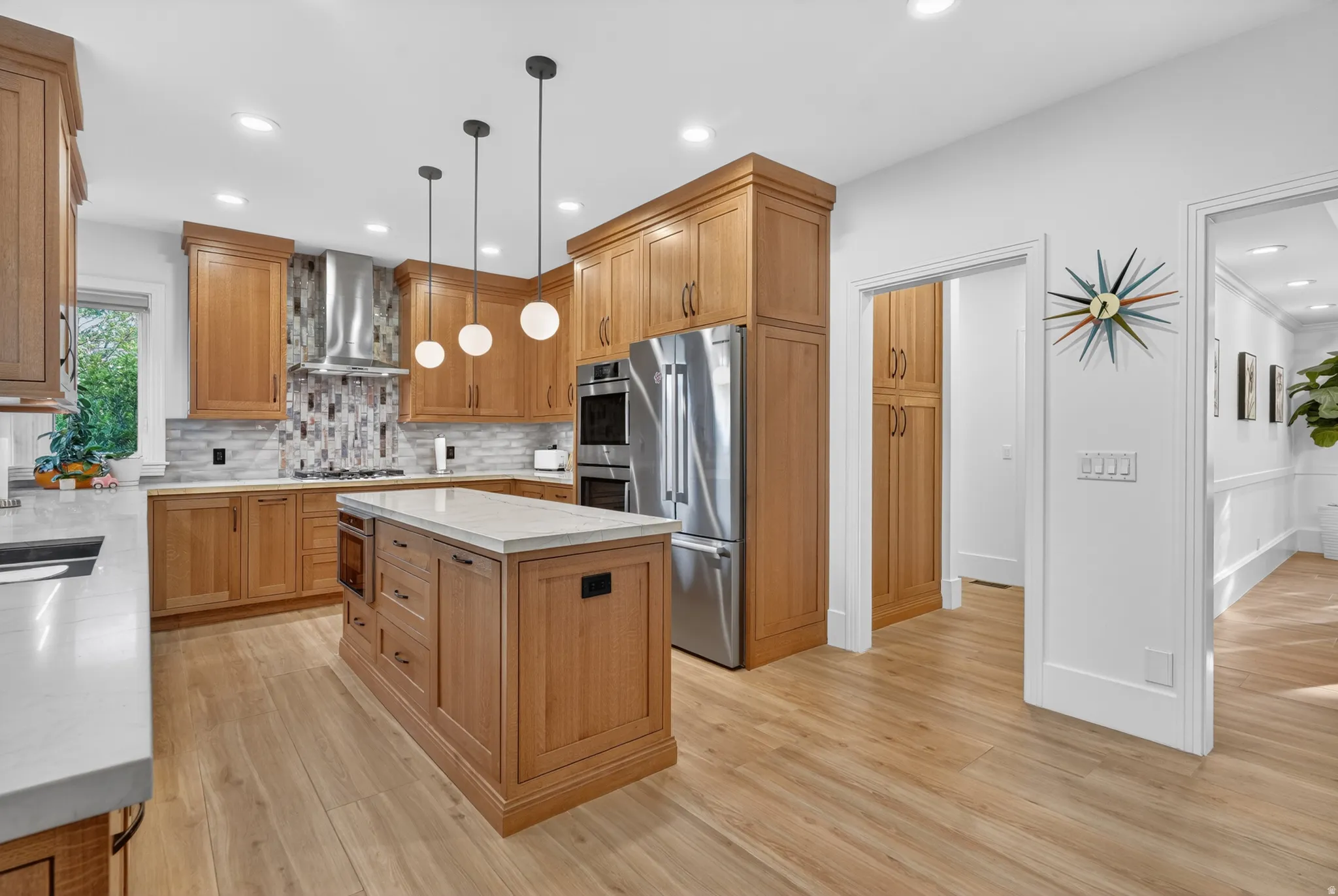 Kitchen featuring wood cabinetry, light countertops, wood-finish flooring, stainless steel appliances, and a central island with integrated oven