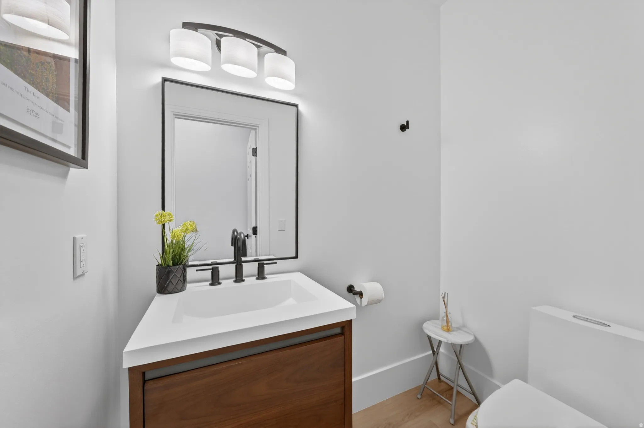 Powder room featuring a modern vanity with a white countertop, an undermount sink, and matte black fixtures