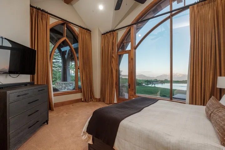 Expansive arched window framing a mountain and lake landscape
