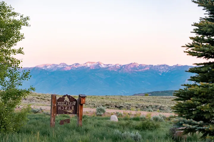 Rustic property signage featuring "Wolf Creek Ranch" with a mountainous backdrop
