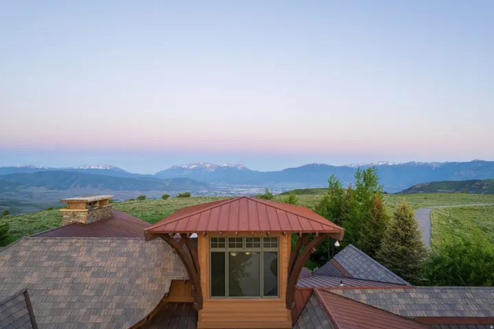 Striking roofline with a copper-colored metal roof accenting a dormer window, complemented by asphalt shingle roofing