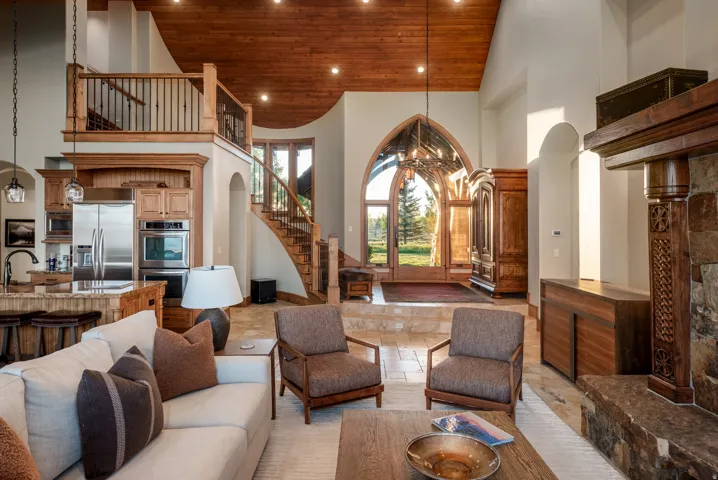 Great room featuring a vaulted wood-finish ceiling, stone tile flooring, and a stone fireplace with a substantial wood mantel