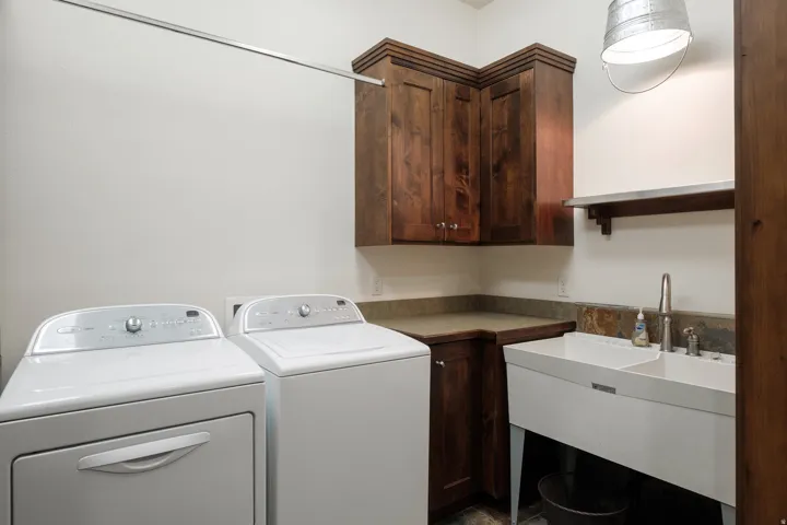 Laundry area featuring rich wood-finish cabinetry and a utility sink