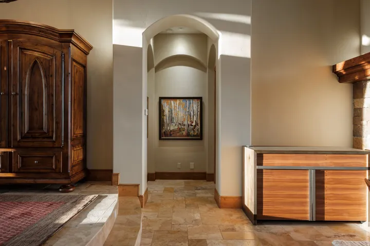 Arched hallway entrance with recessed lighting and natural stone flooring