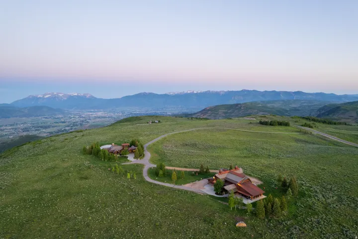 Expansive property featuring two distinct structures nestled amidst rolling green hills