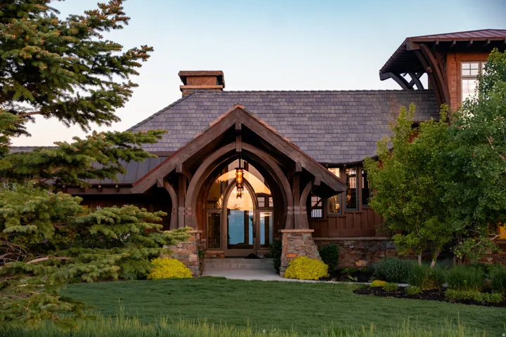 Arched timber entry with stone columns and a carved wood door
