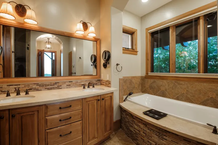 Dual vanity featuring undermount sinks, stone countertops, and wood-finish cabinetry
