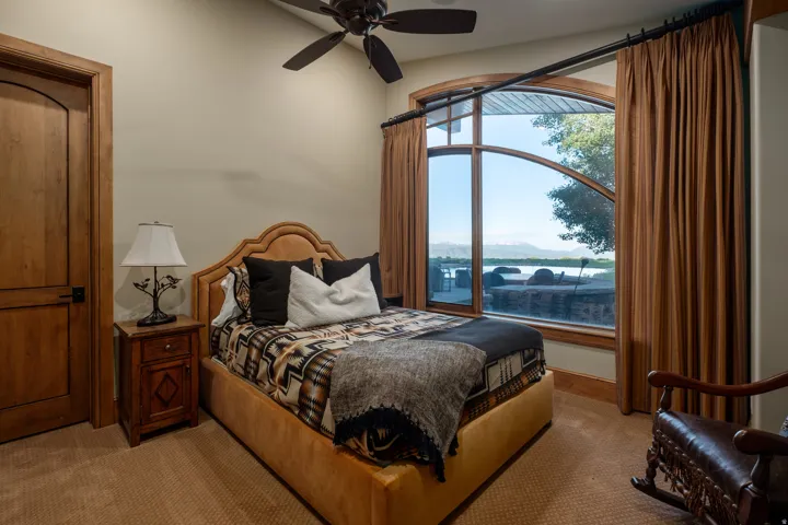 Arched picture window framing a serene water feature and distant mountains