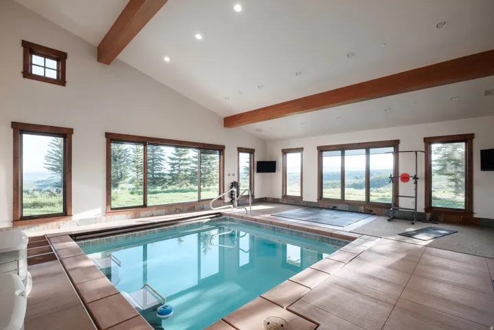Indoor swimming pool featuring a tiled surround and natural light from multiple windows