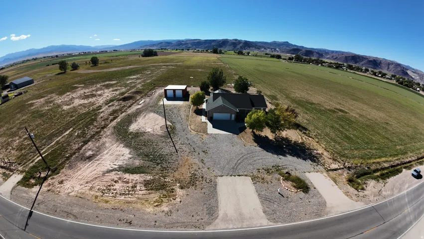 Expansive property featuring a single-story residence with an attached garage, a detached two-bay structure, and a gravel driveway