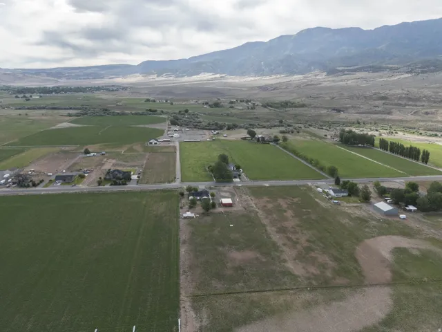 Expansive rural property featuring multiple agricultural fields, distant mountain range, and scattered residential structures