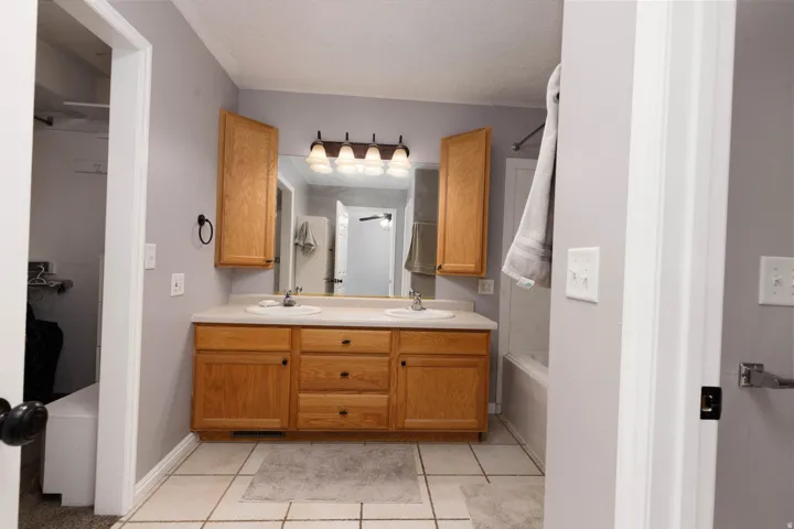 Bathroom featuring a double vanity with light wood cabinetry, dual undermount sinks, and a light-toned countertop