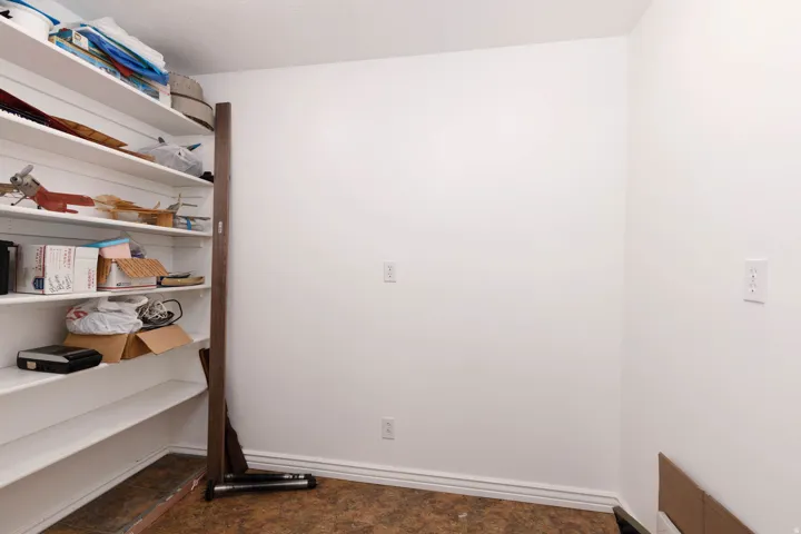 Built-in shelving unit with multiple white shelves, light-colored walls, and textured flooring