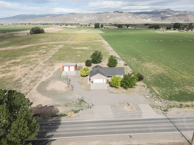 Ranch-style residence featuring an attached two-car garage, a detached two-bay garage, mature landscaping, and a gravel driveway