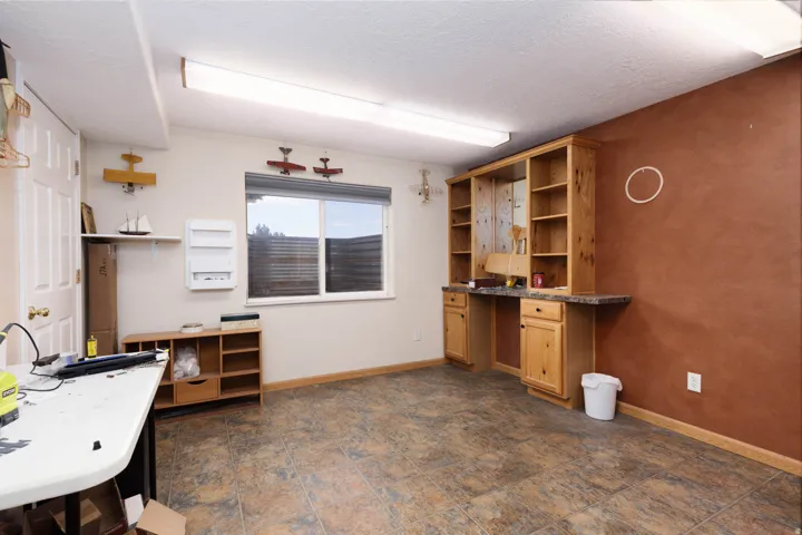 Spacious room featuring wood-finish flooring and a built-in wooden desk with integrated shelving