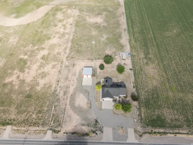 Aerial view showcasing a single-story residence with a dark gray shingle roof and an attached garage