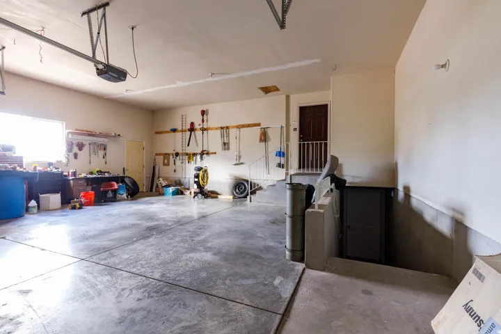 Spacious garage featuring concrete flooring, an overhead garage door opener system, a window providing natural light, and a dedicated entry door