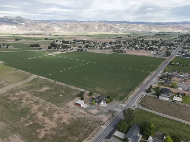 Expansive land parcel featuring existing structures, including a single-story residence and a red shed