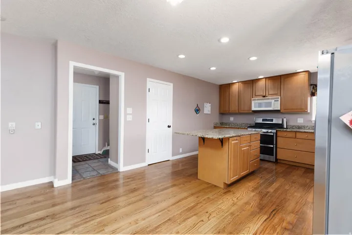 Kitchen featuring wood-finish flooring, recessed lighting, and a center island with an extended countertop