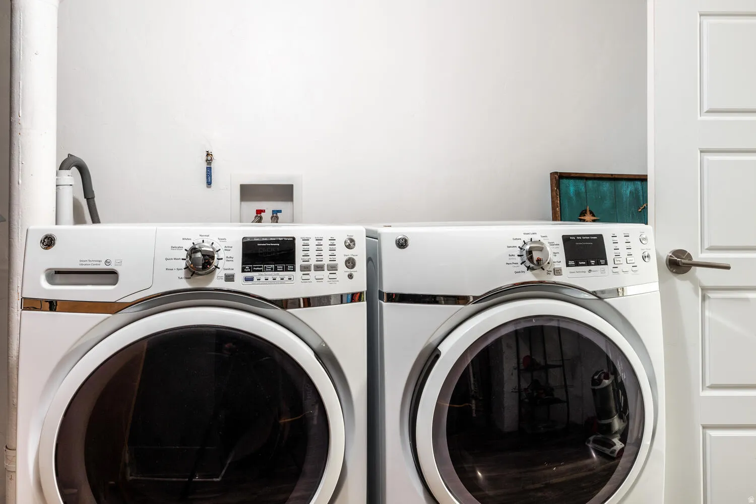 Dedicated laundry area featuring a front-loading washer and dryer, white paneled door, and neutral wall finish