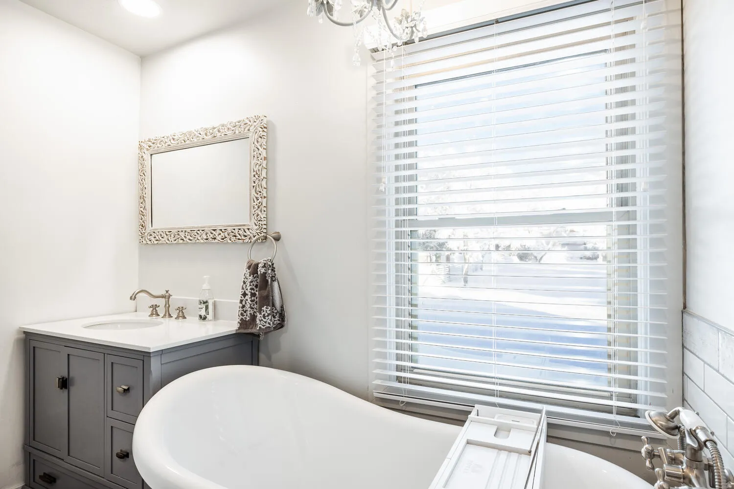 Freestanding soaking tub with a large window featuring horizontal blinds