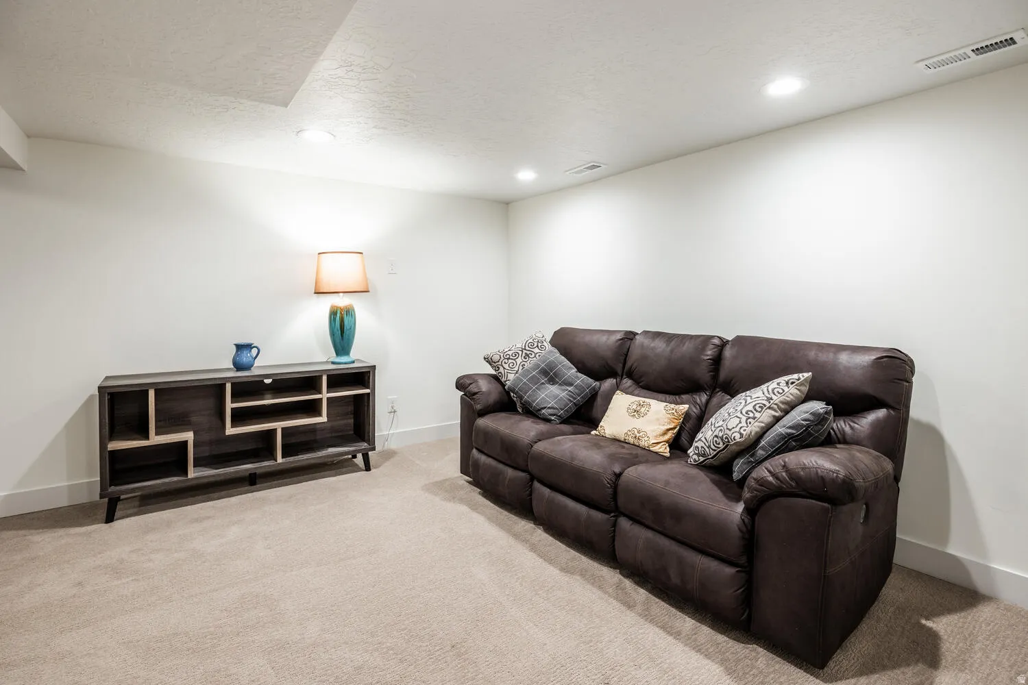 Neutral-toned carpeting extends throughout this room, complemented by white walls and recessed ceiling lighting