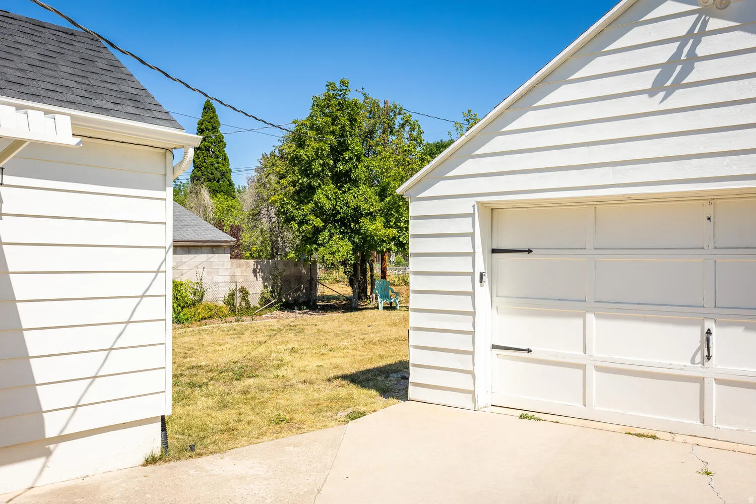 Detached garage featuring white horizontal siding and a panel-style garage door with decorative black hardware