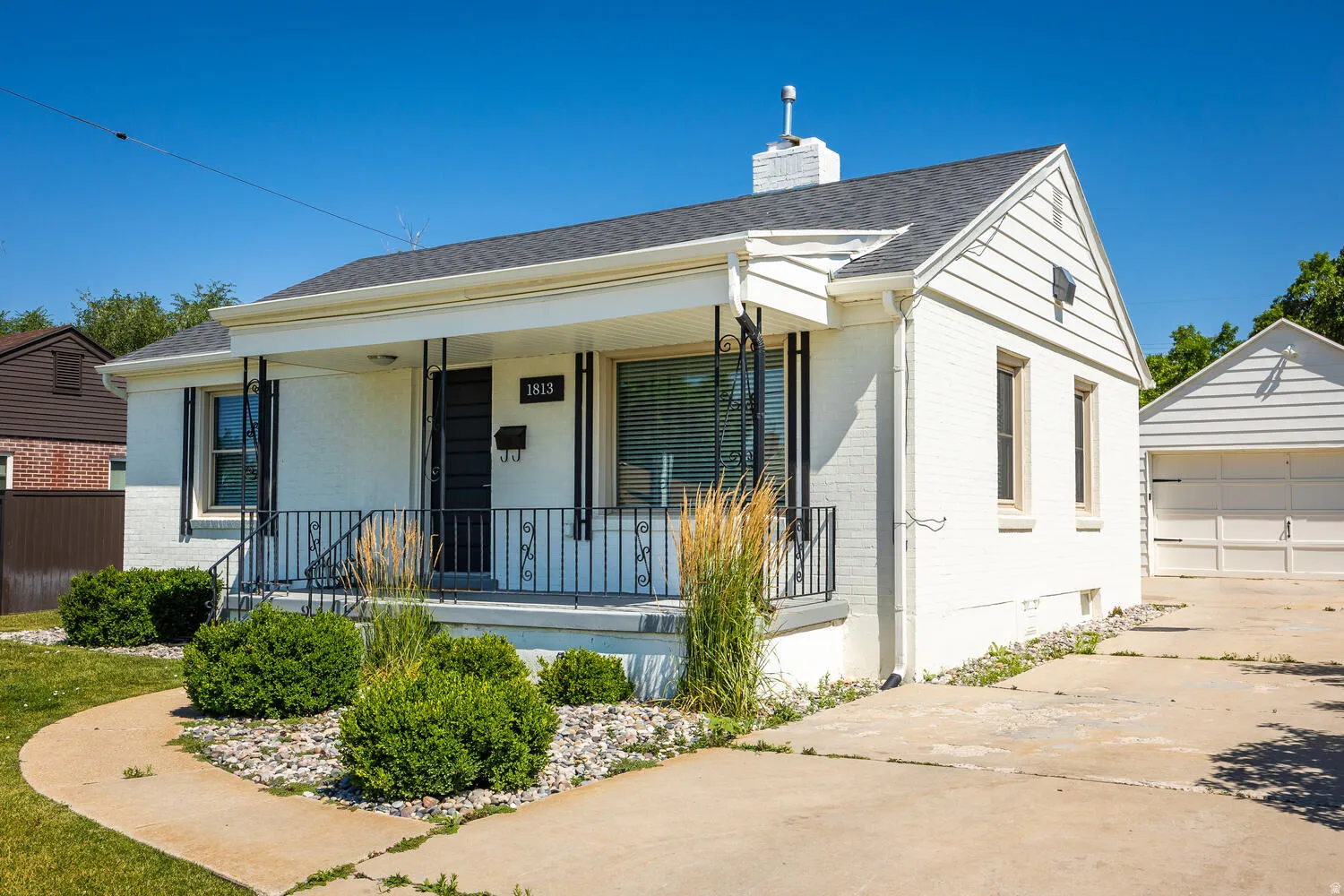 White exterior with a covered porch featuring black wrought iron railings
