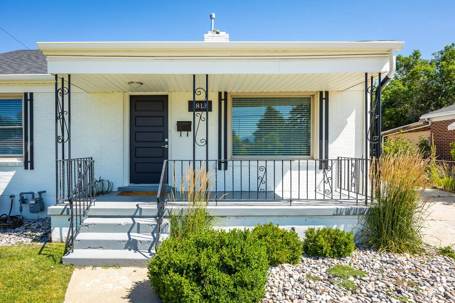 White exterior featuring a covered front porch with black iron railings and decorative posts