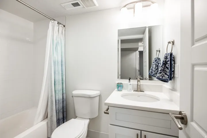 Bathroom featuring a white vanity with an integrated sink, brushed nickel faucet, and a wall-mounted mirror