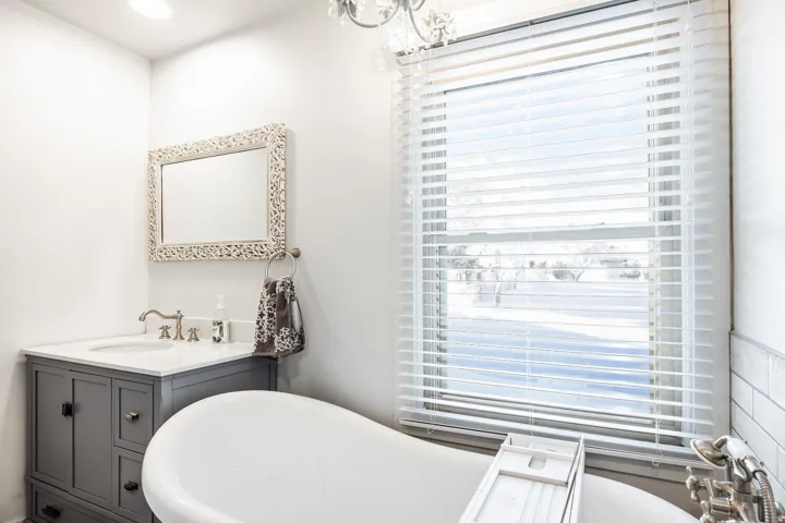 Freestanding soaking tub with a large window featuring horizontal blinds