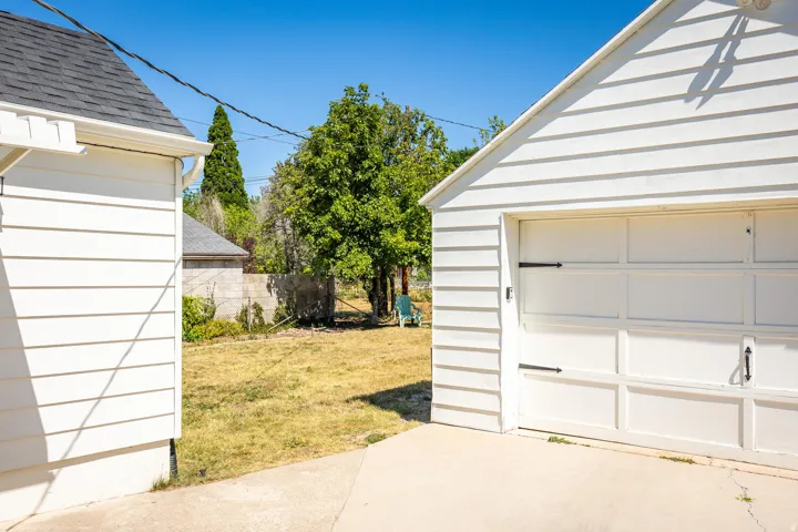 Detached garage featuring white horizontal siding and a panel-style garage door with decorative black hardware