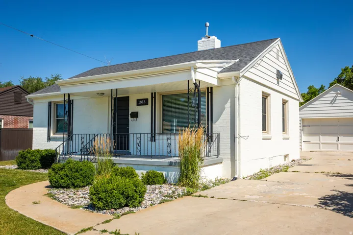 White exterior with a covered porch featuring black wrought iron railings