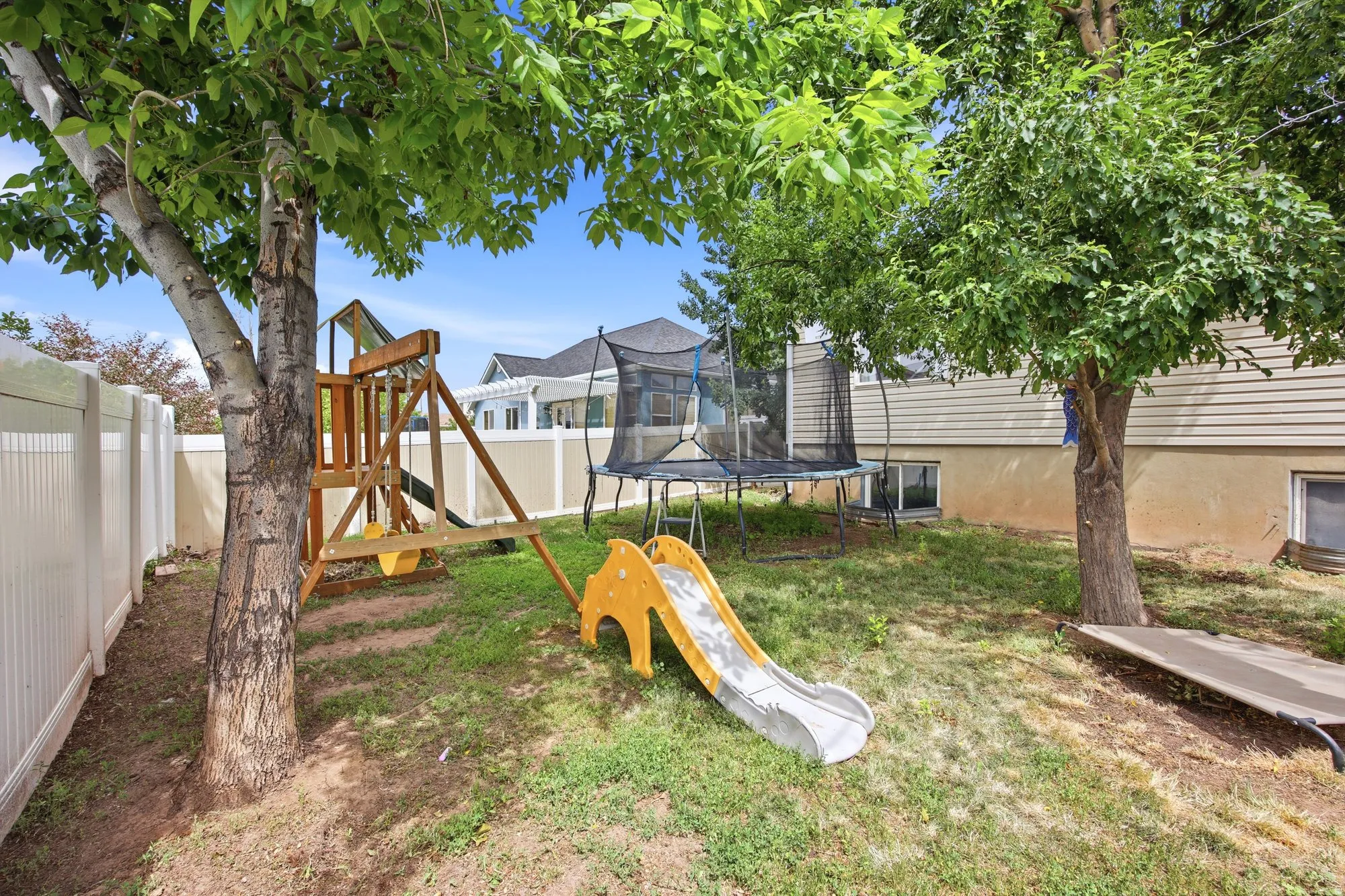 Spacious rear yard with established trees and a white privacy fence