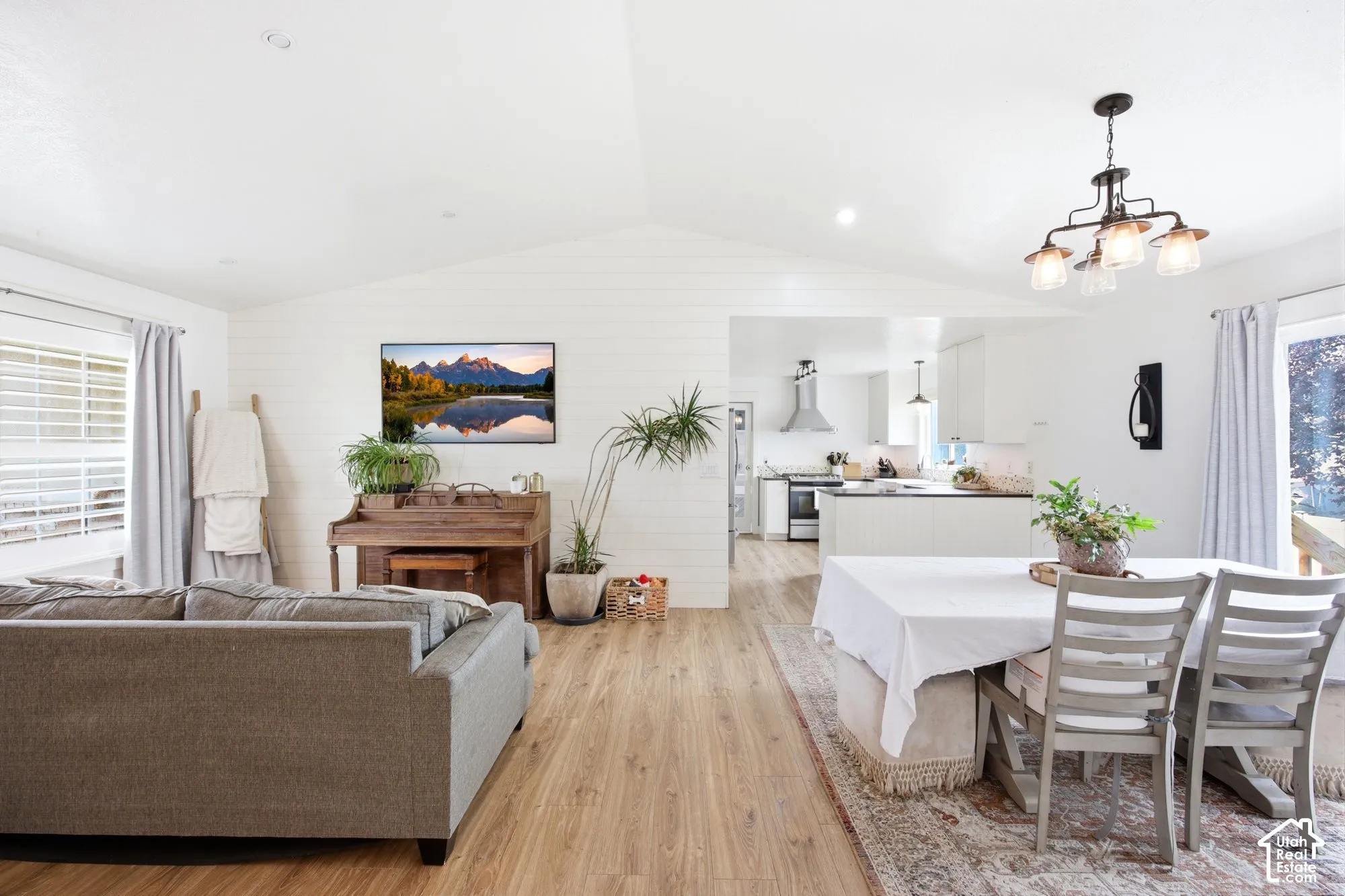 Open-concept living area with vaulted ceilings, wood-finish flooring, and white shiplap accent walls