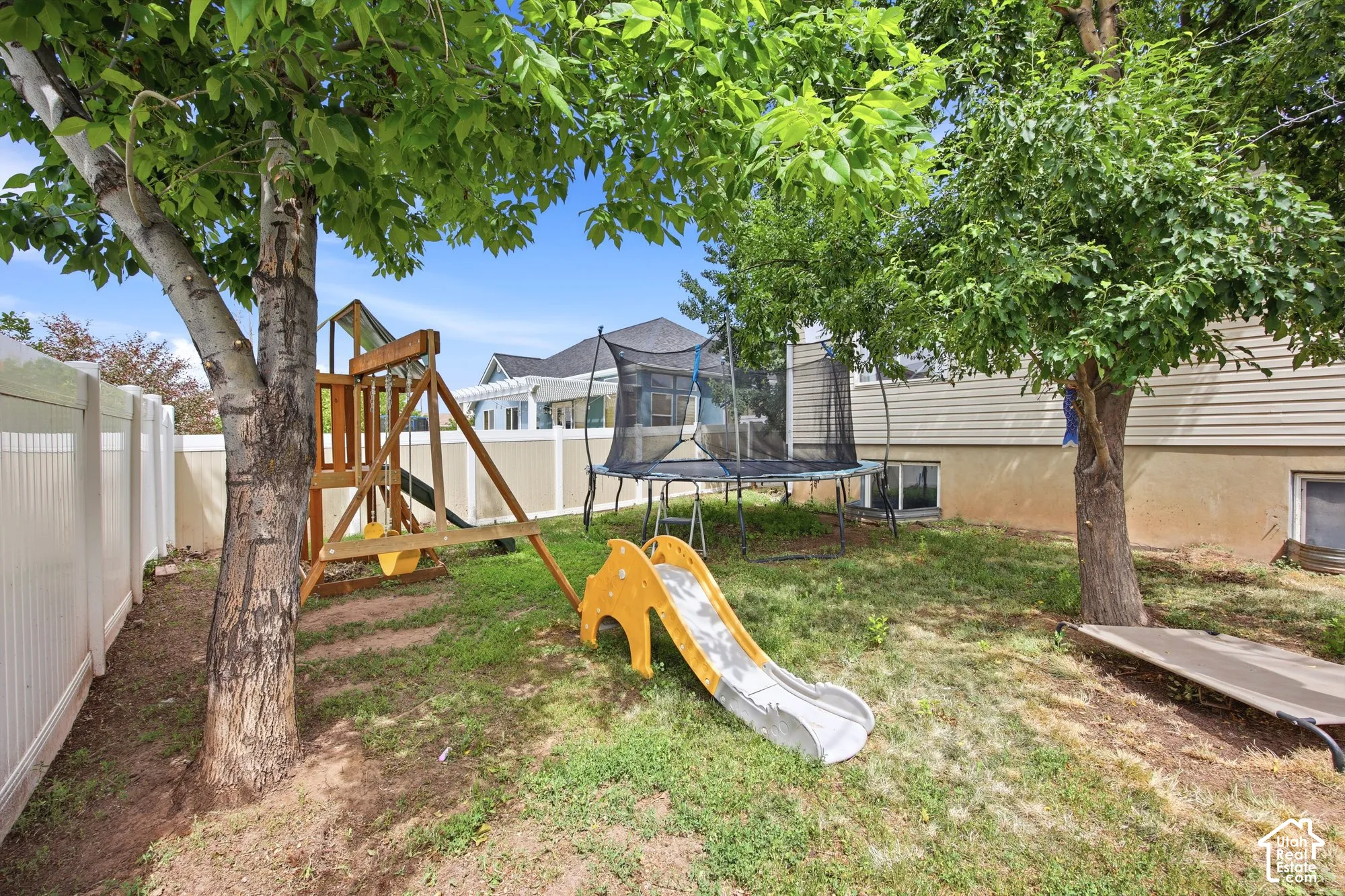 Spacious rear yard with established trees and a white privacy fence