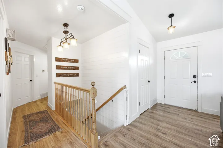 Entryway featuring wood-finish flooring, white shiplap accent wall, white paneled doors, and a staircase with a natural wood handrail and balusters