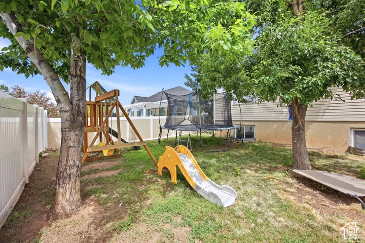 Spacious rear yard with established trees and a white privacy fence