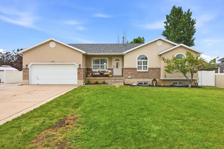 Stucco exterior with brick accent, a two-car garage, and a concrete driveway