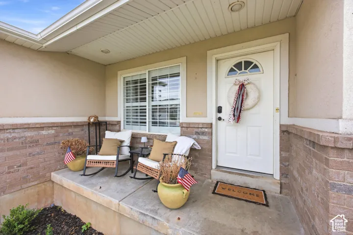 Covered porch featuring a brick facade and stucco exterior