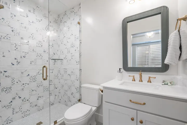 Glass-enclosed shower with patterned tile surround and a built-in shelf