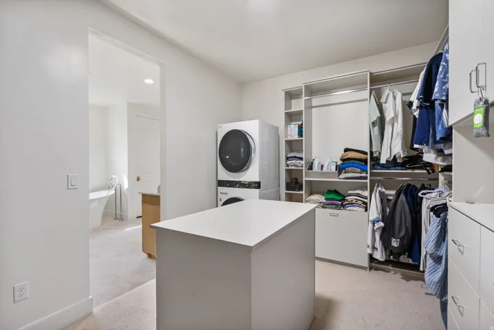 Walk-in closet featuring an integrated island, custom shelving, and hanging rods